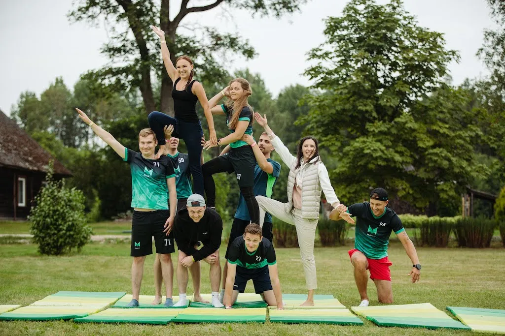 The Mitigate team outdoors, stacked into a human pyramid on gym mats