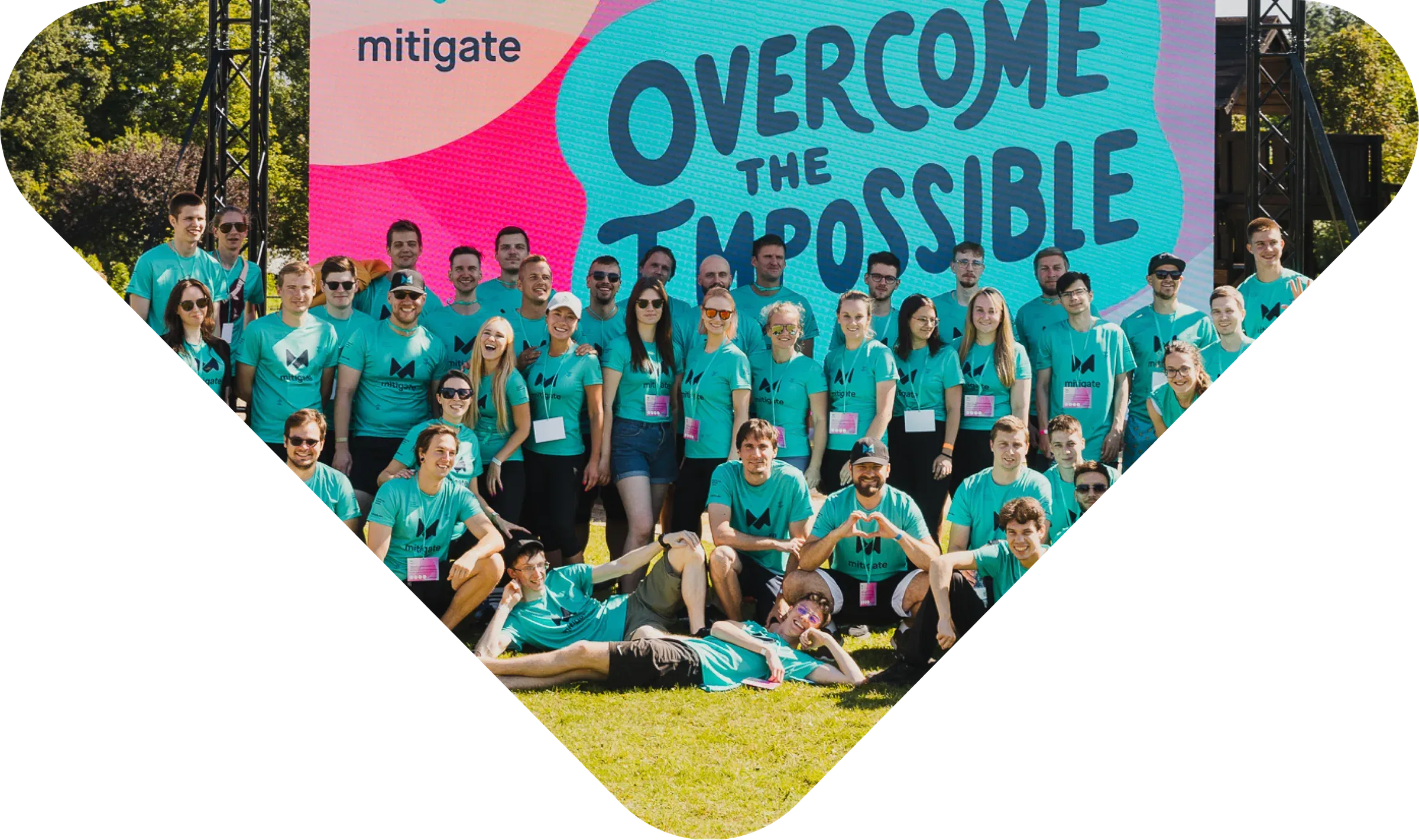 The Mitigate team gathered in front of an “Overcome the impossible” banner at a company event